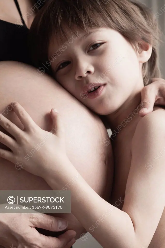 Boy embracing mother´s pregnant belly, cropped