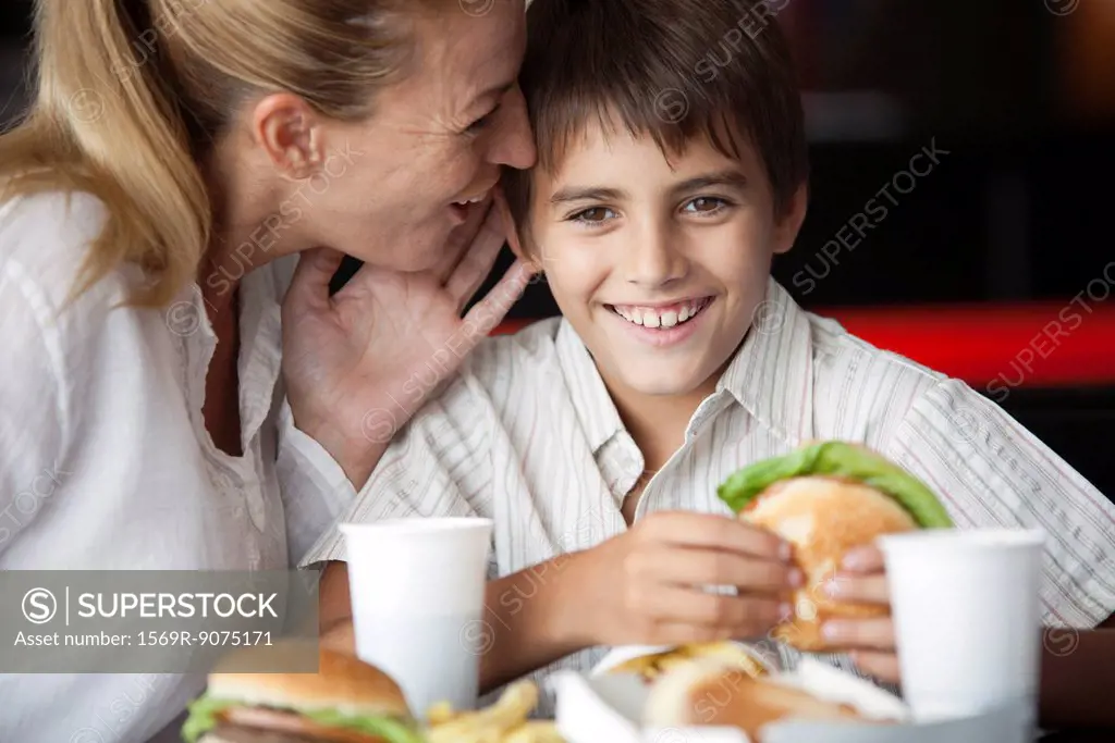 Mother whispering in son´s ear in fast food restaurant