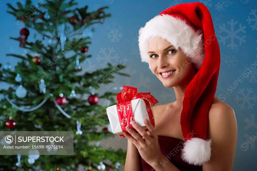 Woman wearing Santa hat and holding Christmas present, portrait