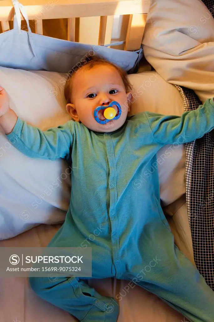 Baby girl in crib, sucking pacifier
