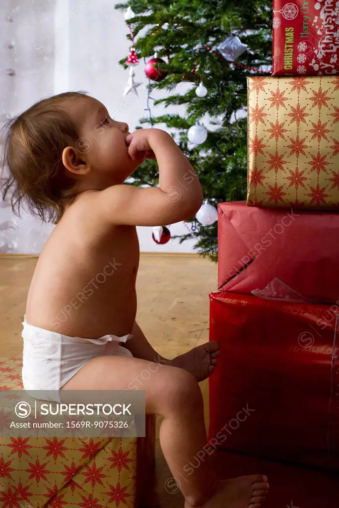 Baby girl contemplating tall stack of Christmas presents