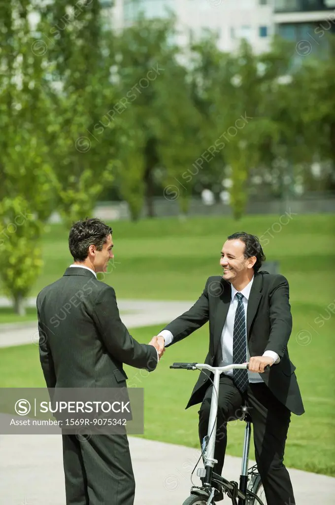 Businessmen greeting each other with handshake, one man on bicycle