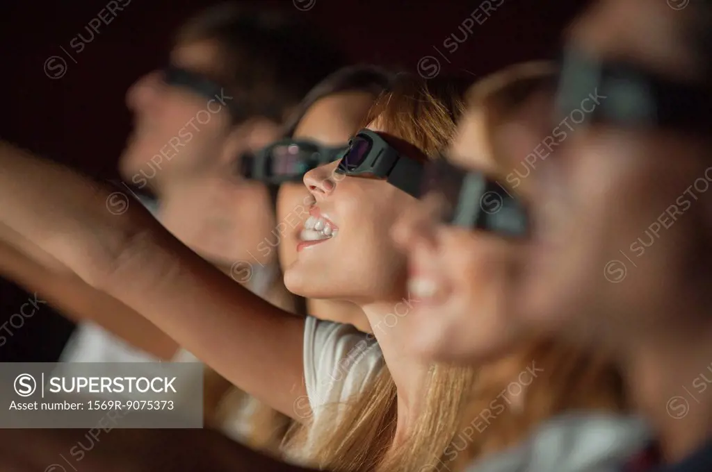Woman wearing 3_D glasses in movie theater, arm reaching out