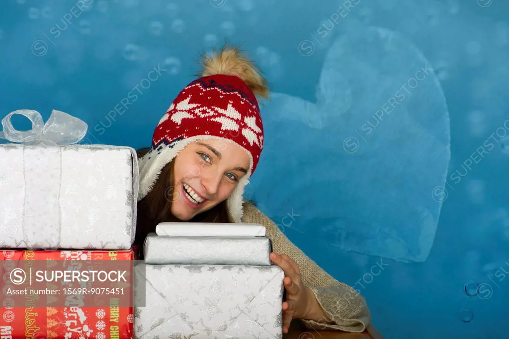 Young woman with stacks of Christmas gifts, portrait