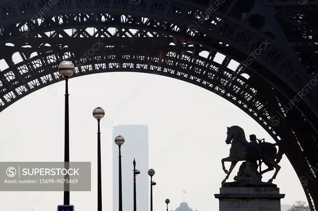 Backlit equestrian statue viewed through arch of Eiffel Tower, Paris, France