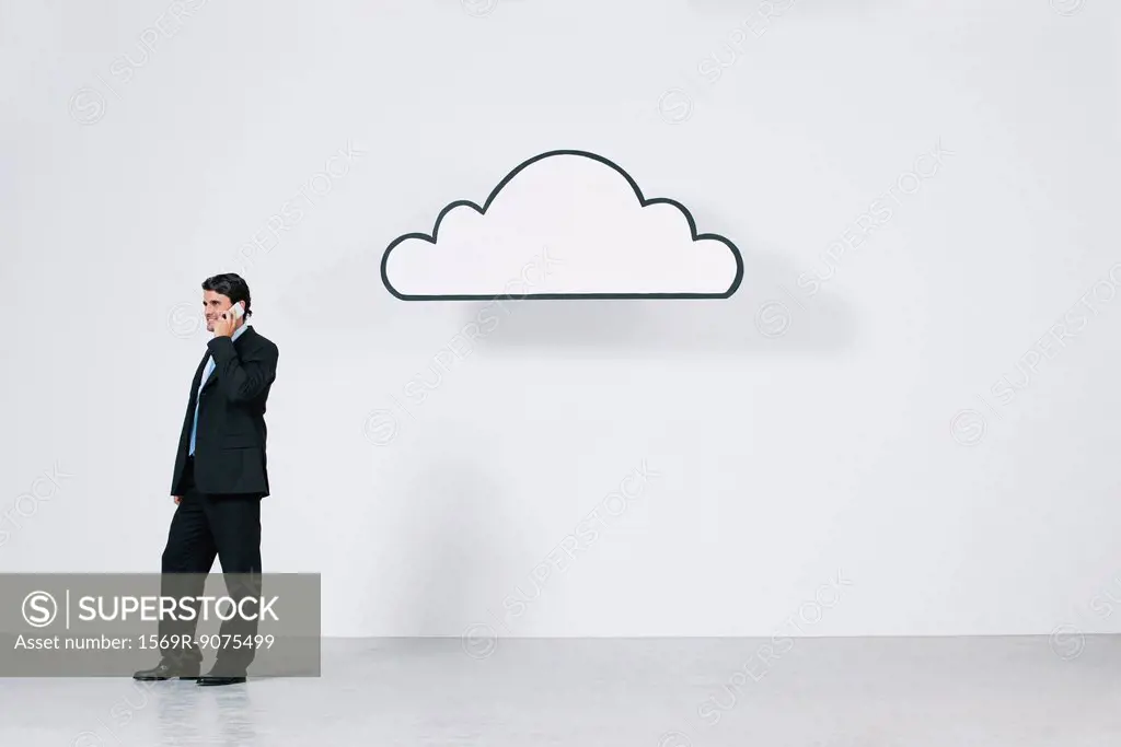 Businessman talking on cell phone near graphic cloud representing cloud computing