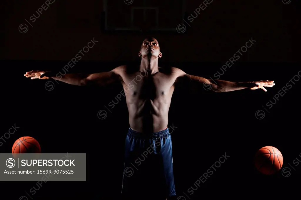 Barechested basketball player dribbling two basketballs