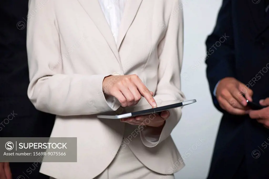 Businesswoman showing digital tablet to colleagues, cropped