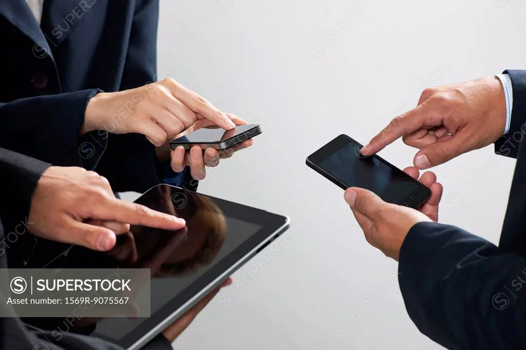 Colleagues exchanging information with smartphones and digital tablet, cropped