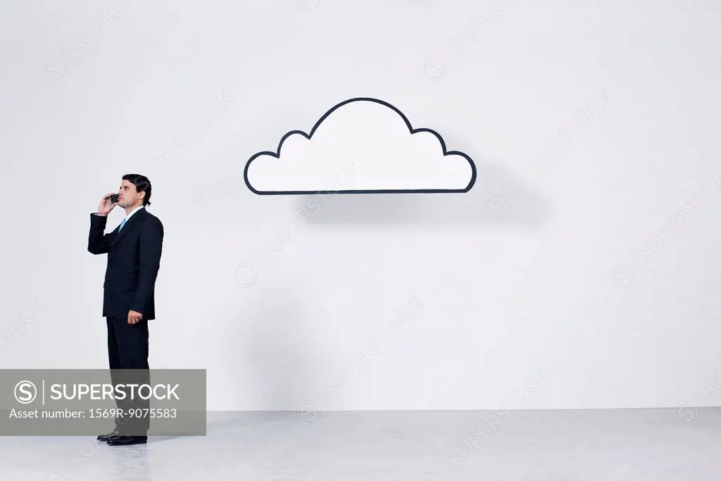 Businessman talking on cell phone near graphic cloud representing cloud computing