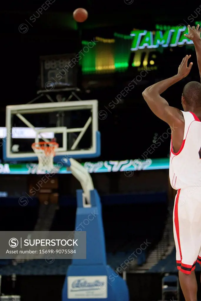 Basketball player shooting basketball, rear view