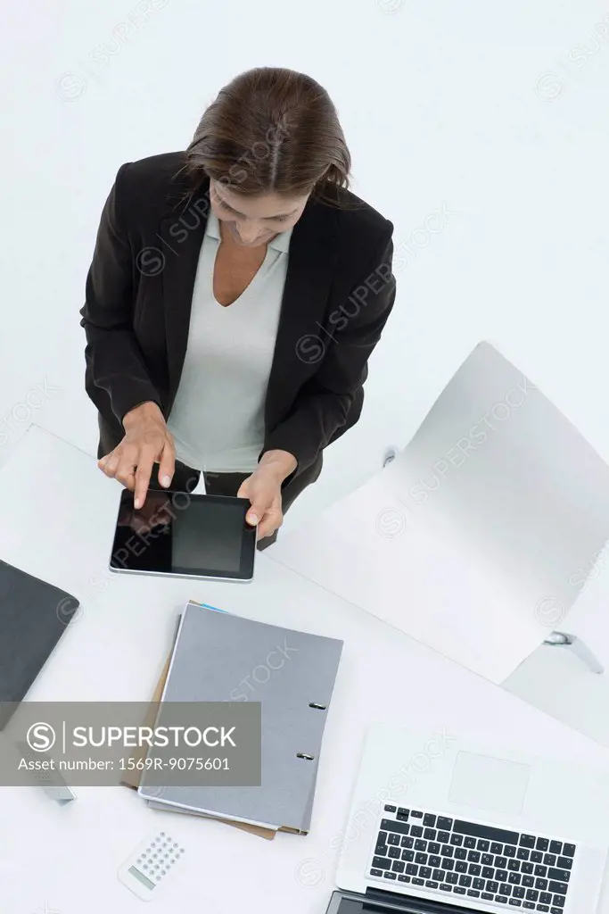Businesswoman standing by desk using digital tablet