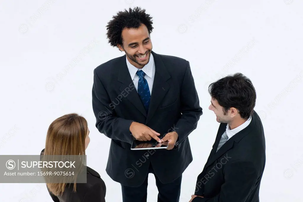 Business associates chatting while colleague uses digital tablet