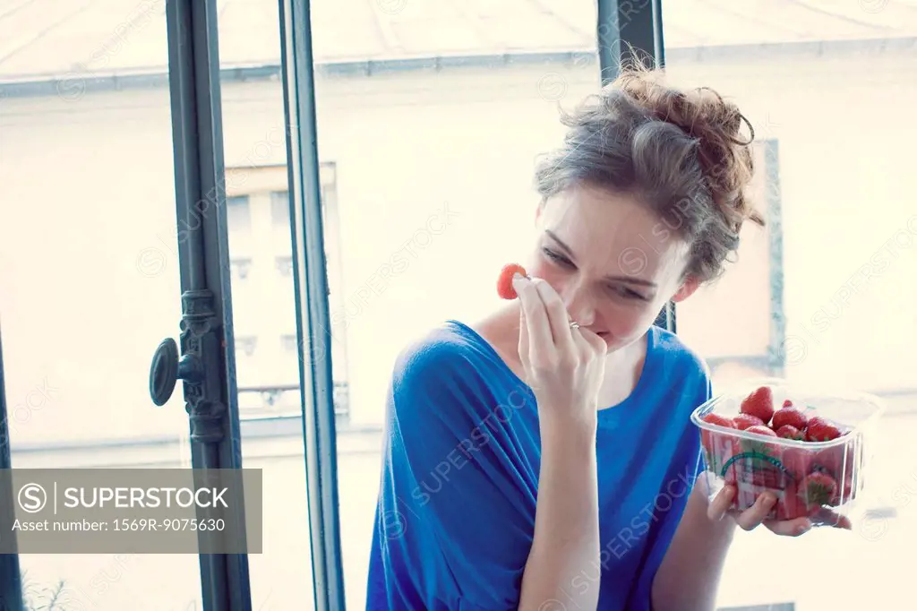 Mid_adult woman laughing while eating strawberries
