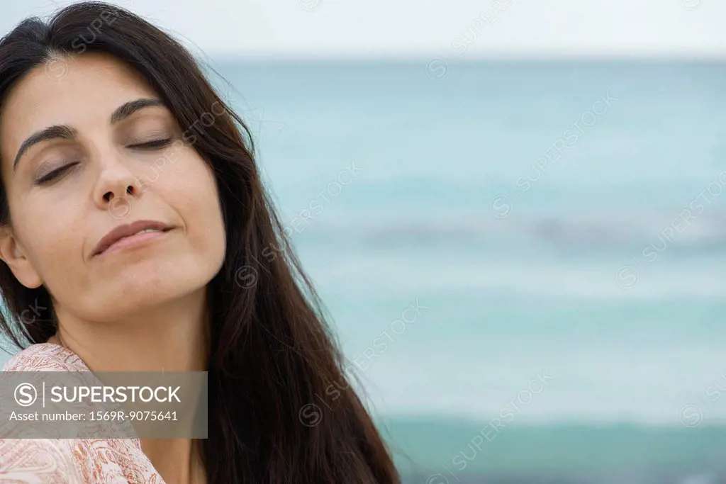 Woman at the beach, eyes closed, portrait