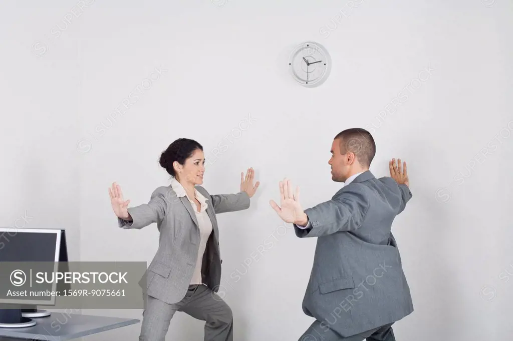 Young businessman and businesswoman exercising in office