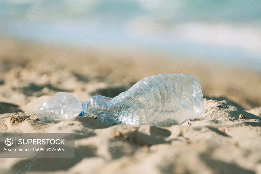 Empty plastic bottle on beach, selective focus