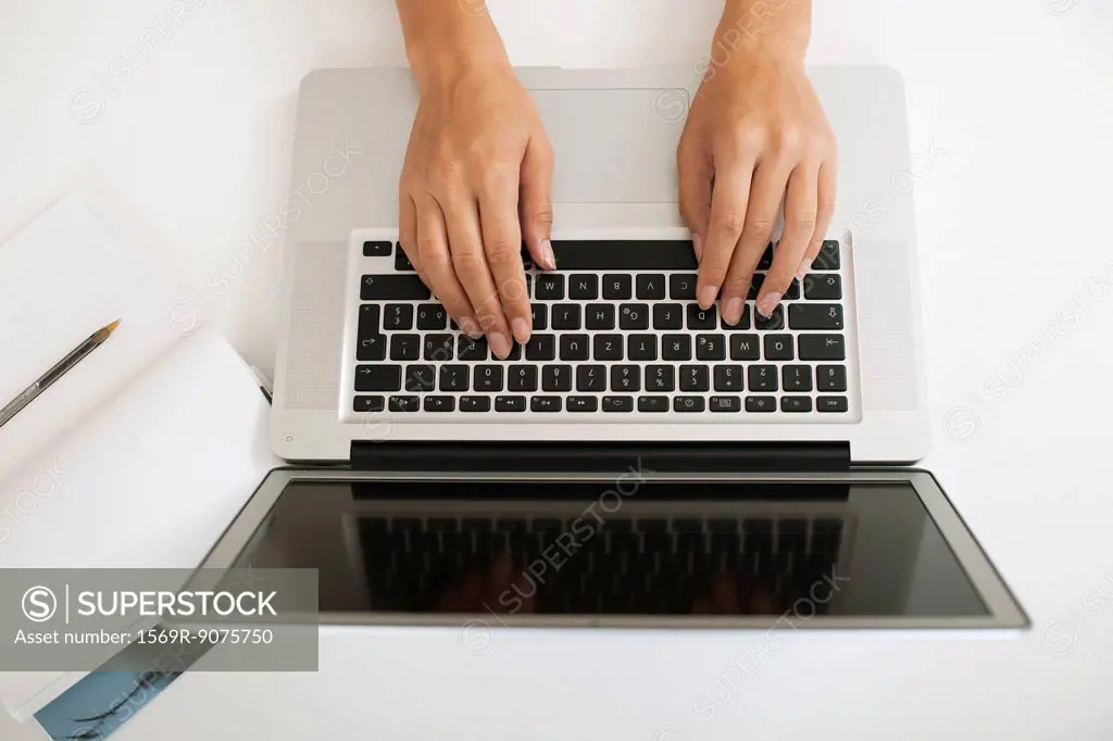 Hands typing on laptop computer, high angle view