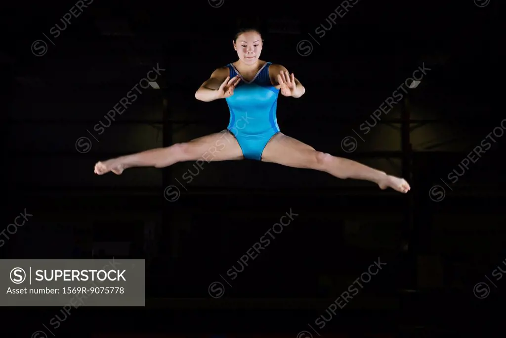 Teenage girl gymnast performing split leap