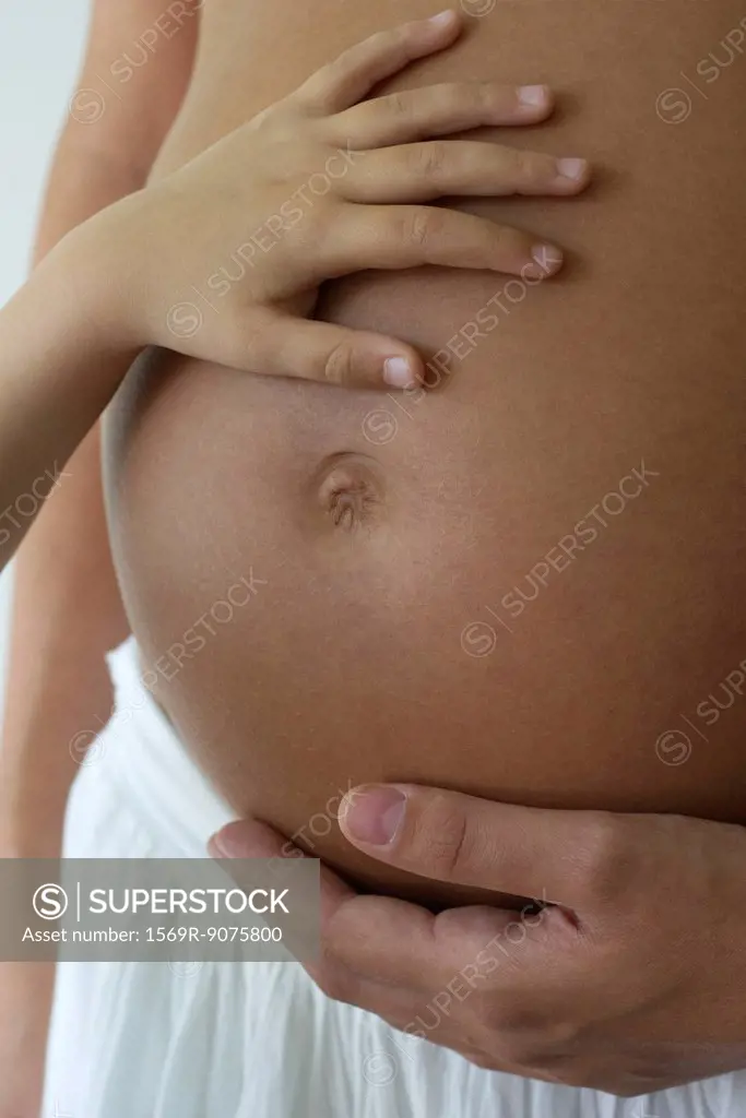 Child´s hand on woman´s pregnant belly, cropped