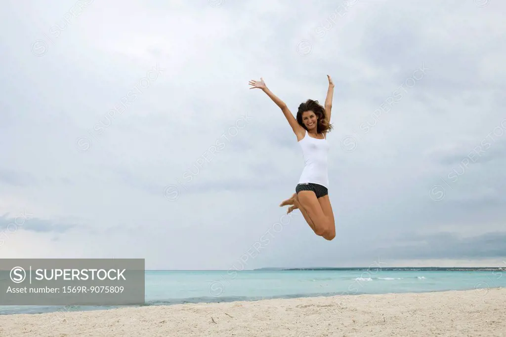 Young woman jumping in air on beach