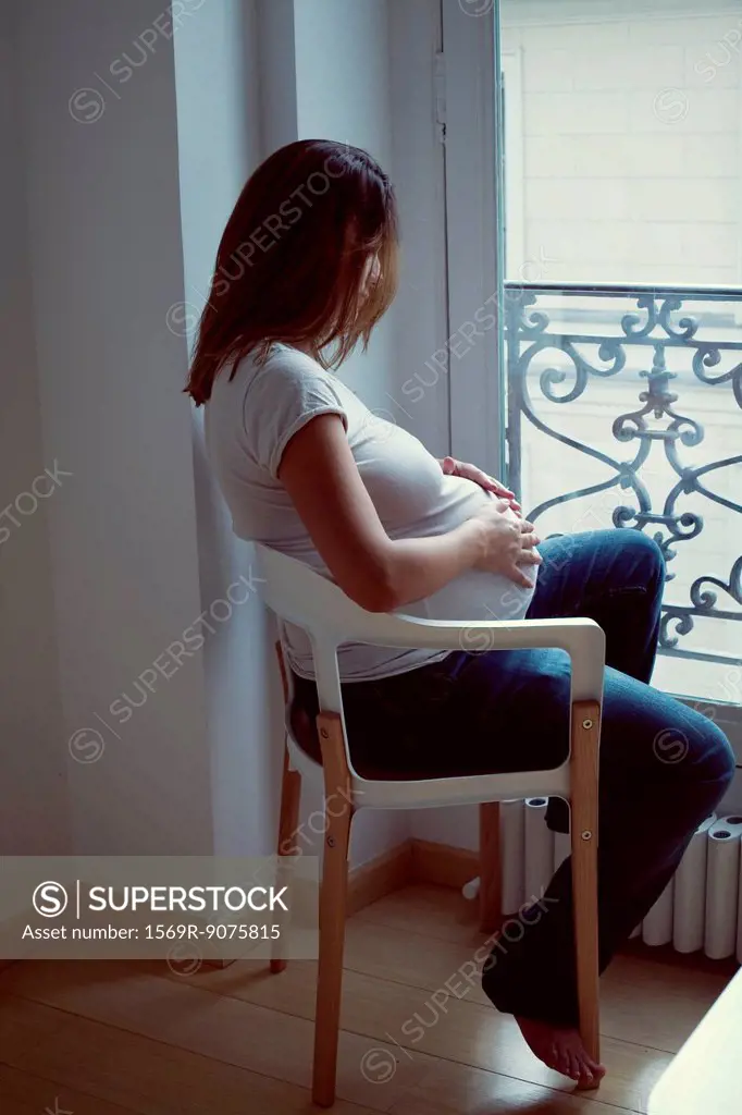 Pregnant woman caressing abdomen, side view
