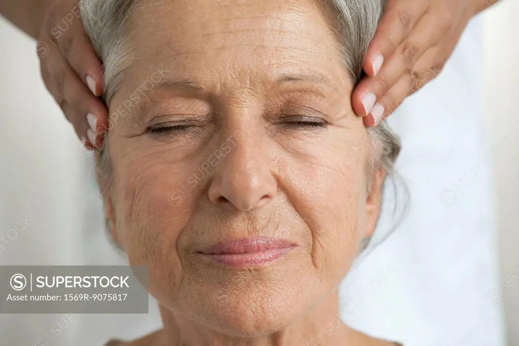 Senior woman having her temples massaged, cropped