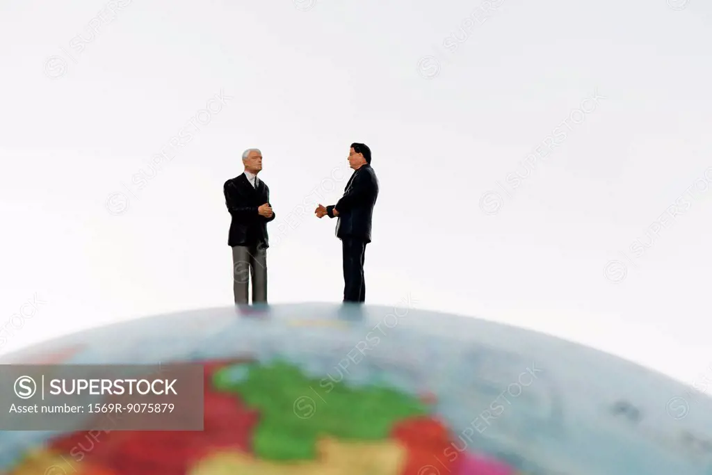 Businessman figurines standing on top of globe