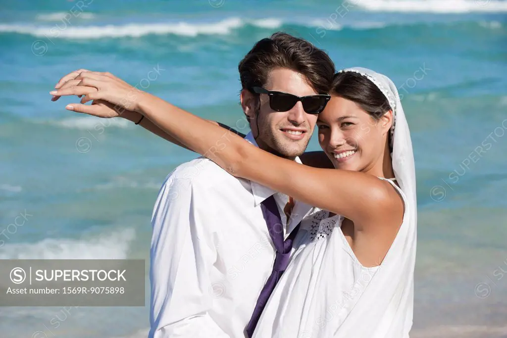 Bride and groom embracing at the beach, portrait