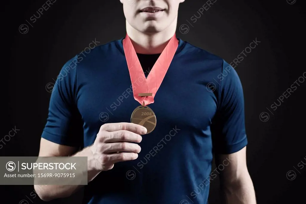 Male athlete holding medal, mid section