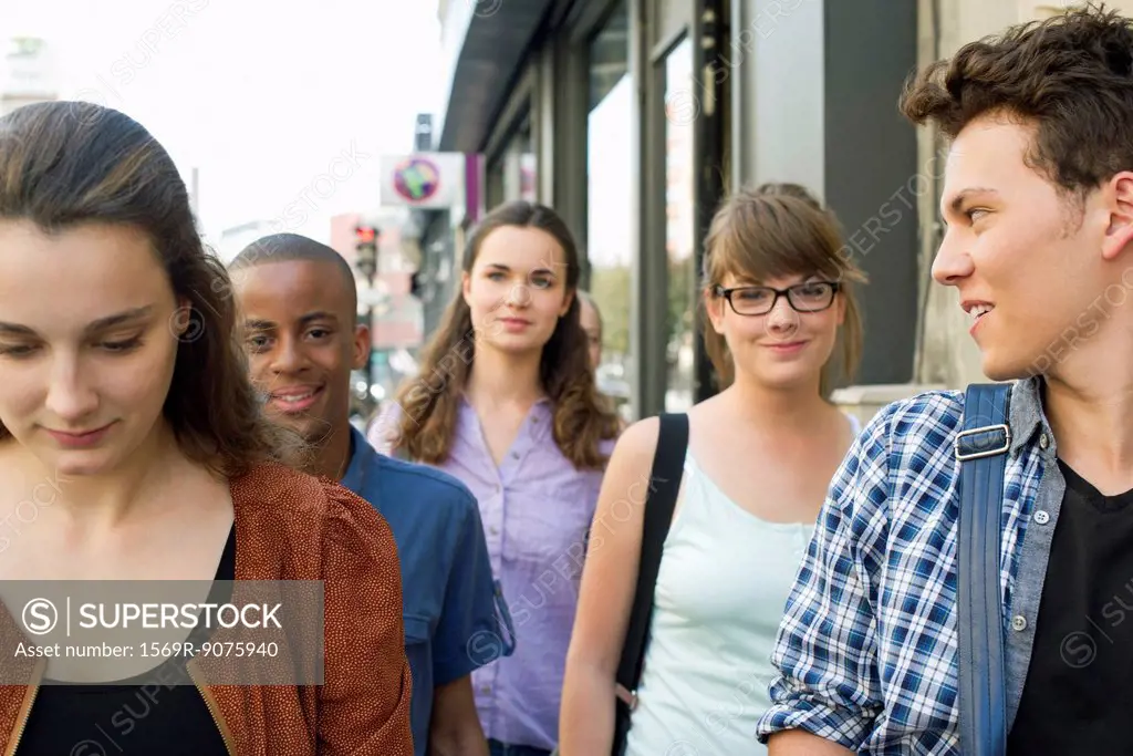 Young adult friends walking together on sidewalk