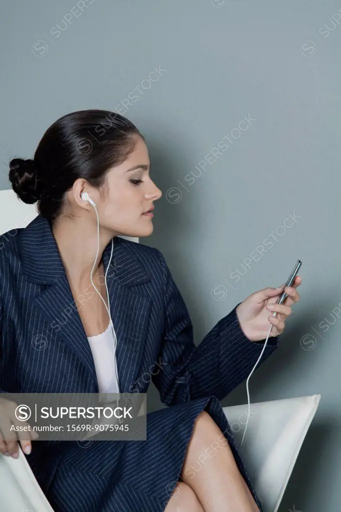 Young businesswoman listening to MP3 player