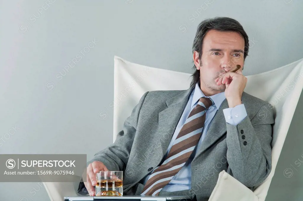Mature businessman relaxing with drink and cigar
