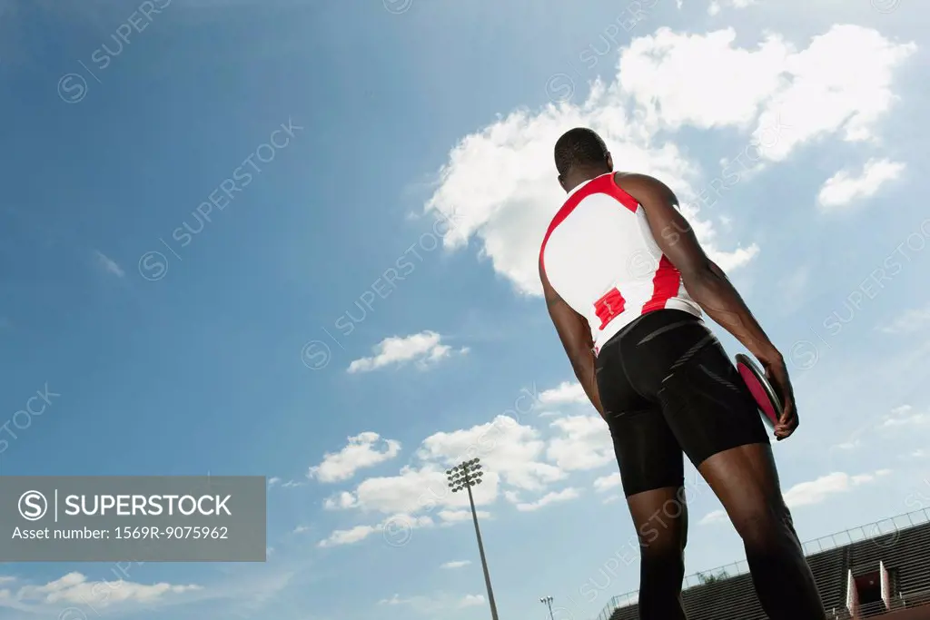 Male athlete holding discus, rear view