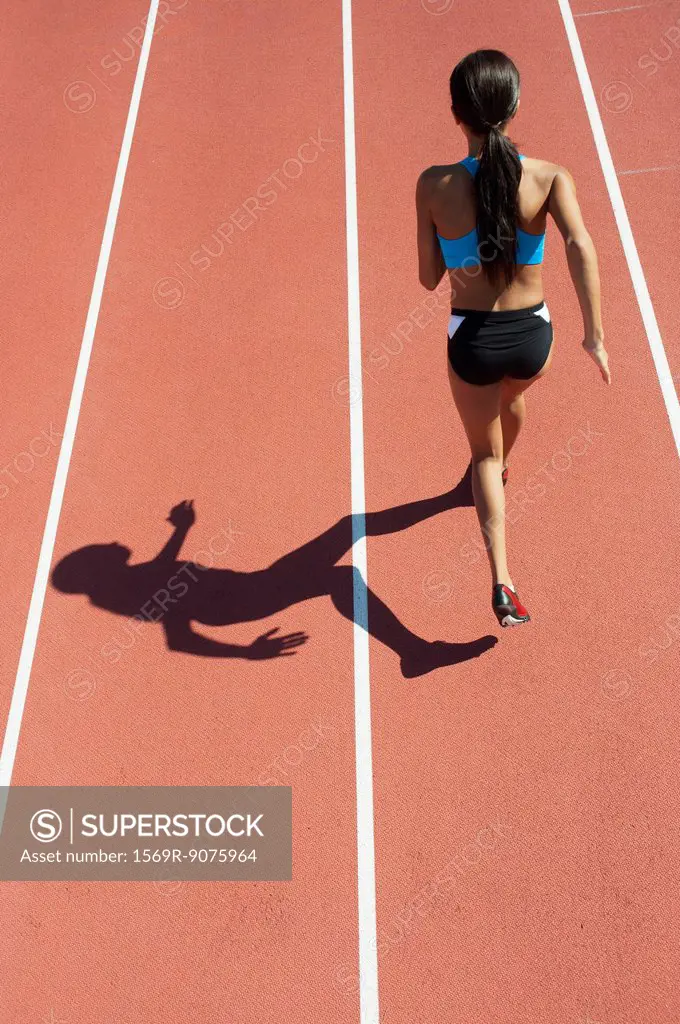 Female athlete running on track, rear view