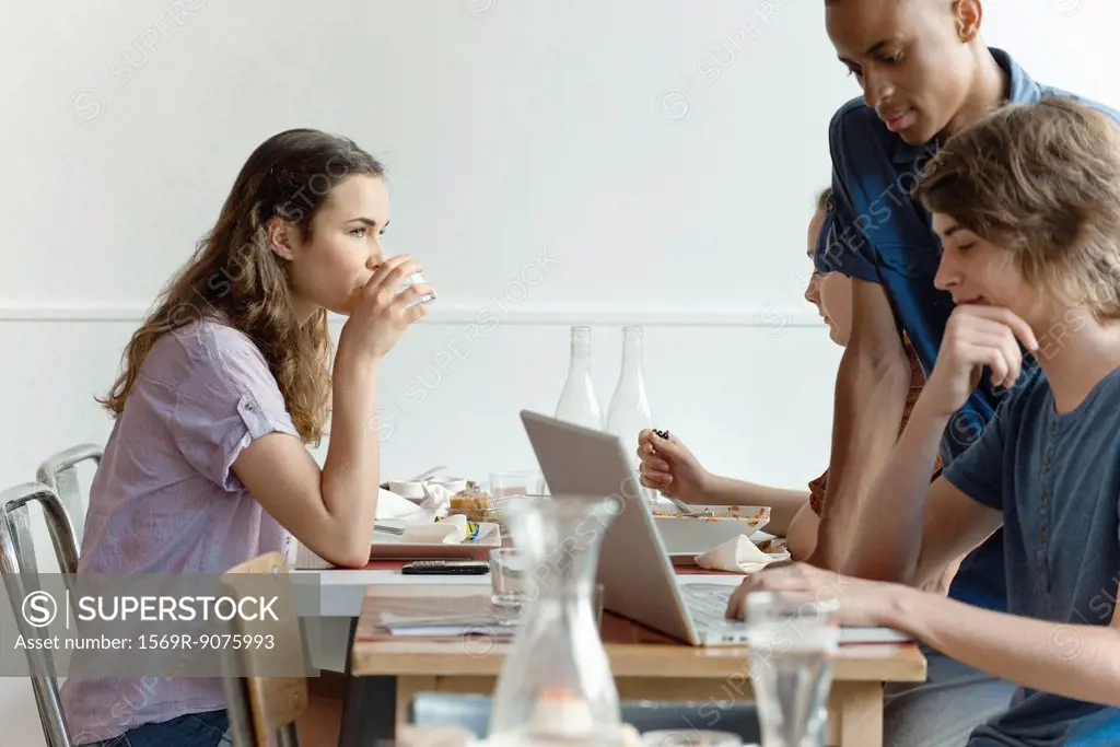 Friends in restaurant, woman dining, man using laptop computer