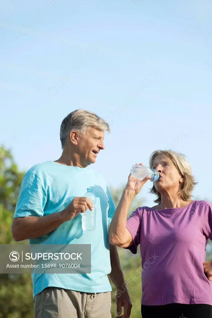 Senior couple drinking bottled water outdoors
