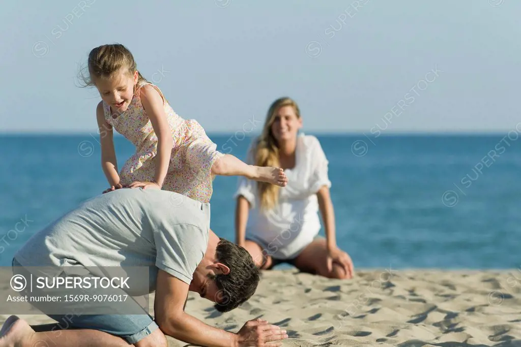 Girl playing with her father at the beach