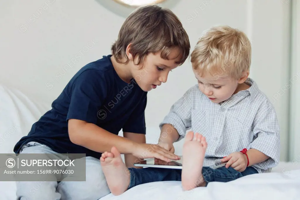 Young brothers playing with digital tablet