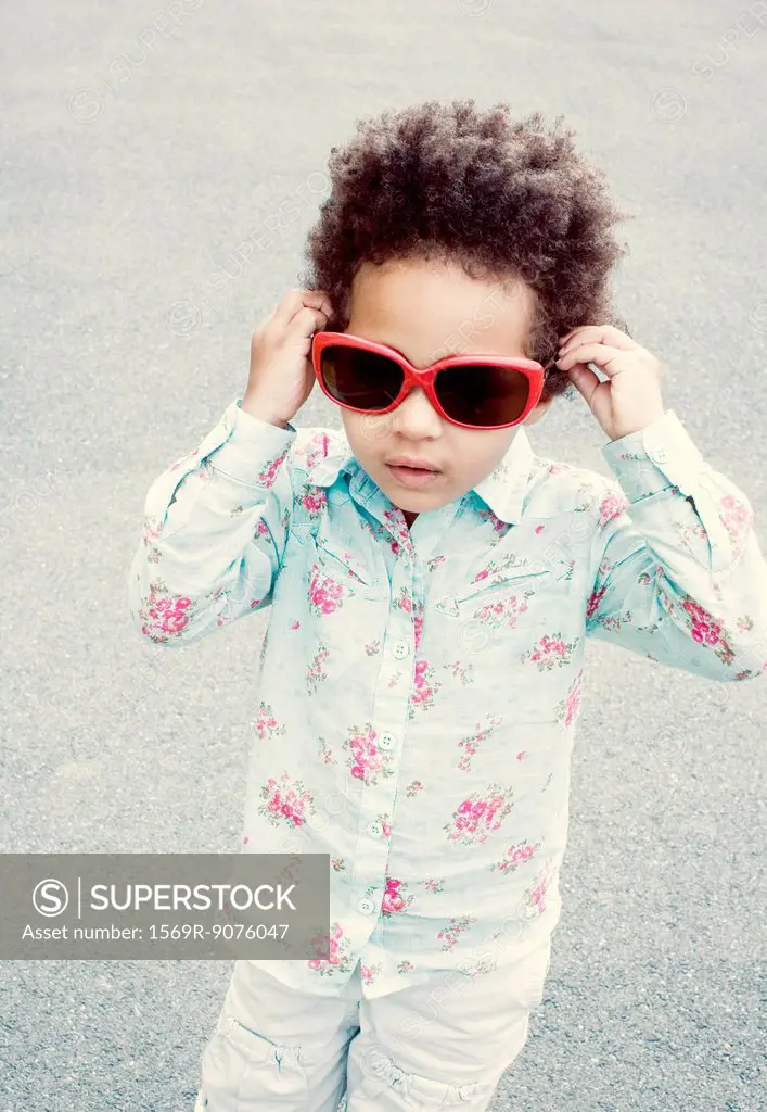 Little girl putting on sunglasses
