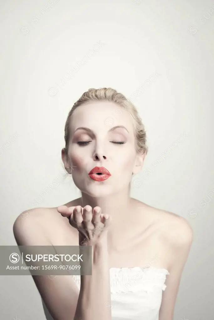 Young woman blowing kiss with eyes closed, portrait