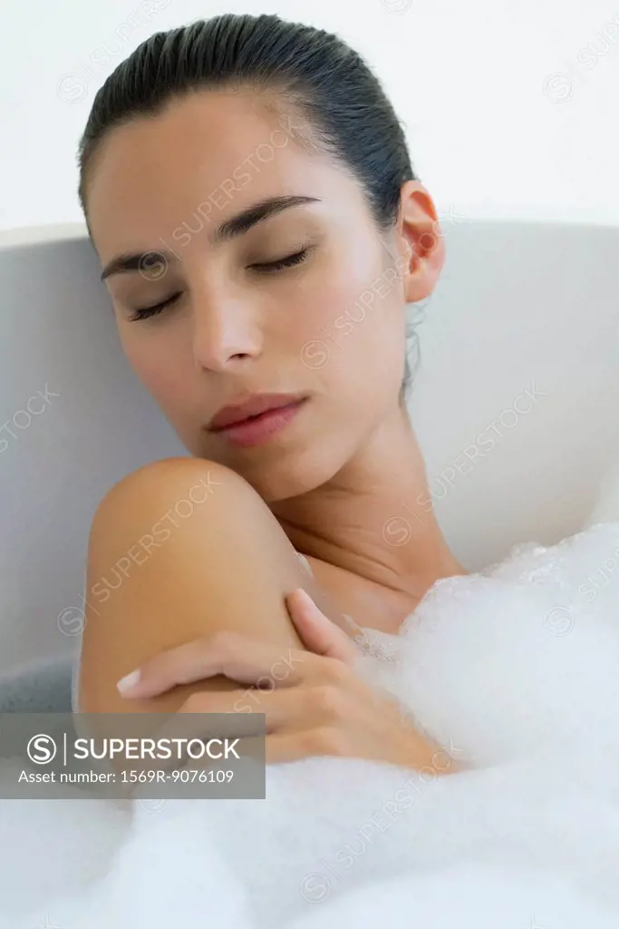 Woman taking bubble bath with eyes closed