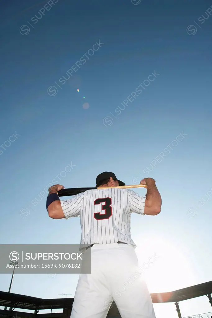 Baseball player holding bat, rear view