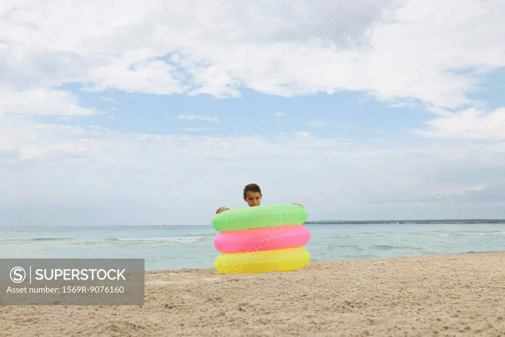 Girl playing with stack of infltable rings on beach