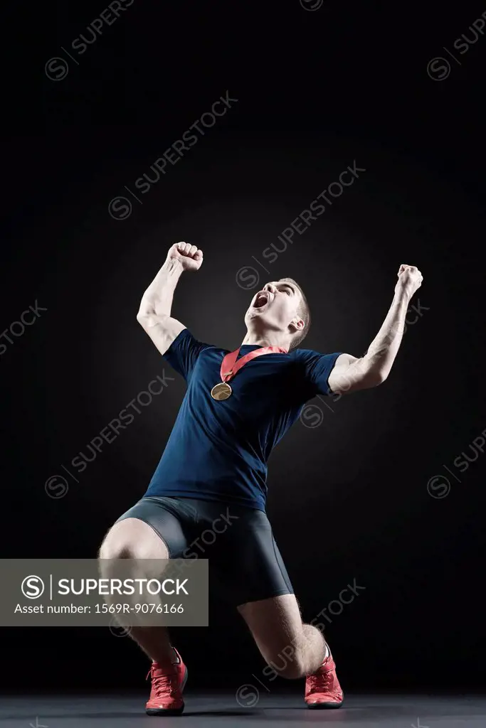 Male athlete shouting with arms raised in victory