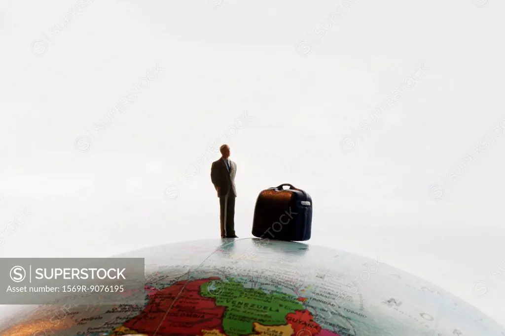Businessman figurine with luggage standing on top of globe