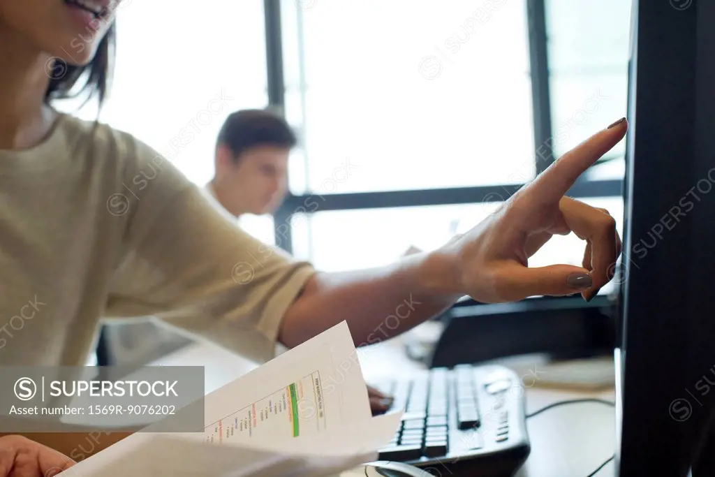 Office worker pointing to computer screen, cropped