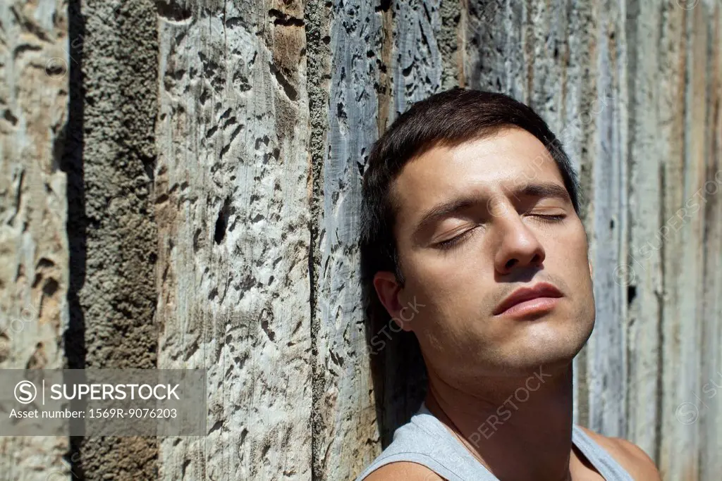 Mid_adult man sunbathing with eyes closed, portrait