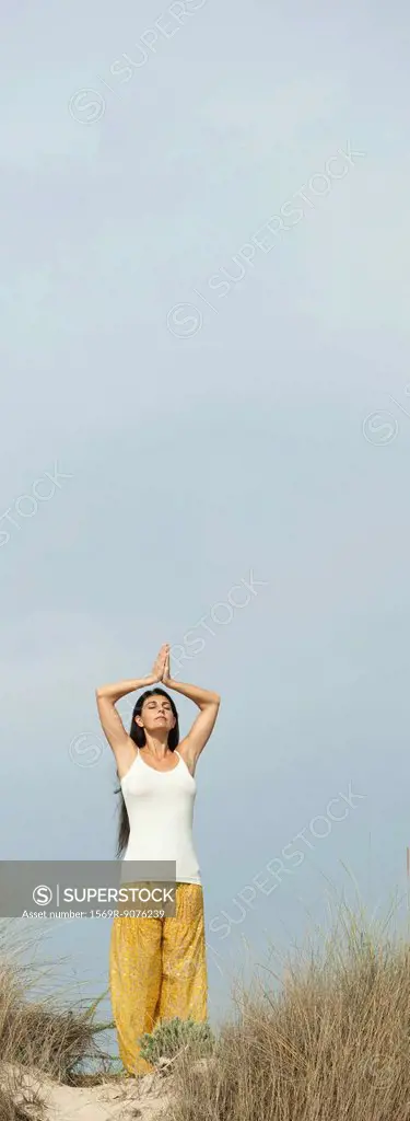 Mature woman doing prayer yoga position on beach