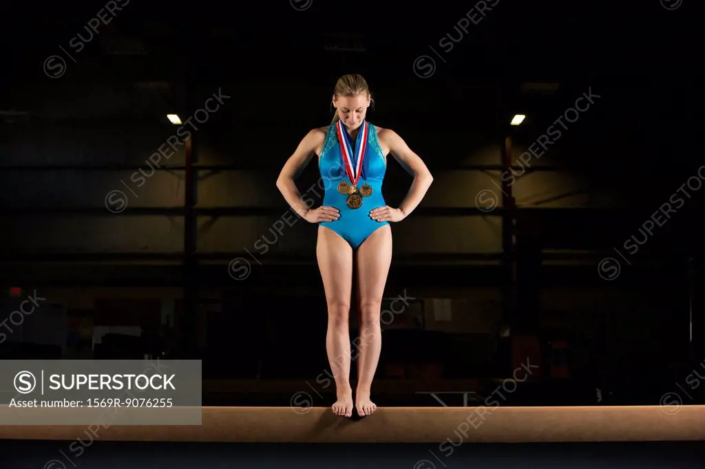Gymnast with medals standing on balance beam